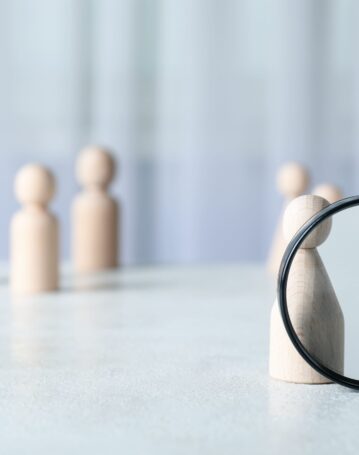 magnifying-glass-and-wooden-figures-on-light-backg-2025-03-25-02-59-22-utc-scaled